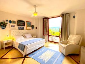 1 dormitorio con 1 cama, 1 silla y 1 ventana en Uma Casa Sobre o Mundo, en Santo Antônio do Pinhal