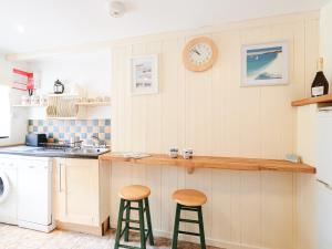 a kitchen with two bar stools and a clock on the wall at Waterside - Ukc4054 in Nancledra