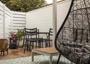 een patio met stoelen, een tafel en een hek bij Bellvilla Suites in Merimbula