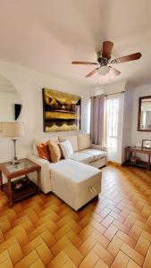 COZY CASITA EN PLAYAS DE TIJUANA في تيخوانا: غرفة معيشة مع أريكة بيضاء ومروحة سقف