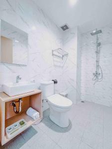 a white bathroom with a toilet and a sink at Hotel Ariandri Puncak in Puncak