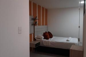 Habitación pequeña con cama con almohadas rojas en Aparta-Estudio, en Medellín