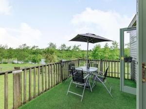 un patio con mesa y sombrilla en Bluebell Lodge, en Holsworthy