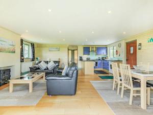 sala de estar con sofás, mesa y cocina en Bluebell Lodge, en Holsworthy