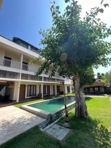 a tree in front of a building with a swimming pool at Locomotive Hotel and Spa by EPS in Nusa Lembongan