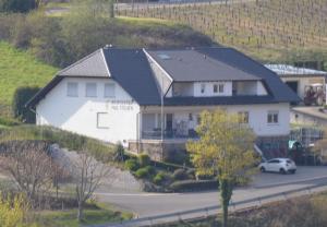 ein weißes Haus mit schwarzem Dach auf einem Hügel in der Unterkunft Weingut Paul Stölben in Briedel