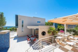 a patio with chairs and umbrellas in front of a house at Apartments DYANA in Novalja