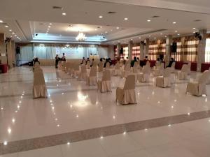 um salão de banquetes com cadeiras e pessoas ao fundo em Golden Dragon Resort em Sing Buri