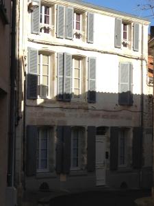 um edifício antigo com janelas e persianas brancas em Appartements d'hôtes Santa Giulia em Niort