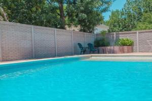 una piscina azul con 2 sillas junto a una valla en Casa Departamento Funes Buena Vista Cochera Pileta en Funes