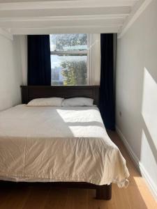 um quarto com uma cama grande e uma janela em Lovely flat near Holland Park em Londres