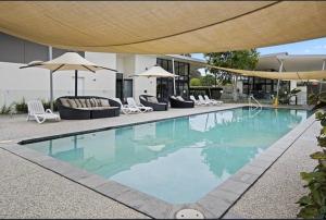 a swimming pool with chairs and umbrellas next to a building at Luxury Tugun property in Gold Coast