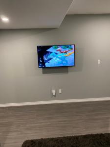 uma televisão de ecrã plano pendurada numa parede branca em 1 Bedroom Modern Secondary Suite em Saskatoon