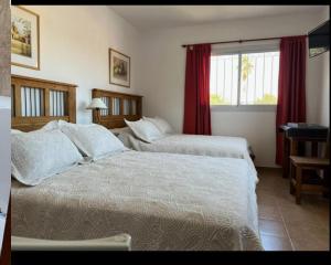 a hotel room with two beds and a window at Posada de Los Lirios in Villa Carlos Paz