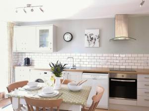 a kitchen with a table and chairs and a kitchen with white appliances at Maple Lodge in Corsham