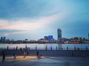 a group of people walking on a sidewalk near a body of water at Shanghai Hidden Garden International Youth Hostel in Shanghai