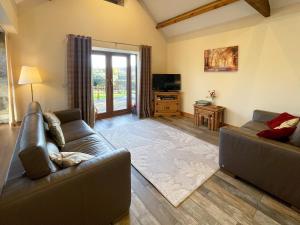 a living room with two couches and a television at The Bobbin in Ashover