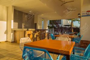 un restaurante con mesas de madera y sillas azules en Planta Baja, a 10 minutos de la playa, Gran alberca y Mini Golf!! en Mazatlán