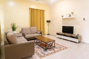 5 Bedrooms Homestay with Private Pool (SEROJA) في نيلاي: غرفة معيشة مع أريكة وطاولة وتلفزيون