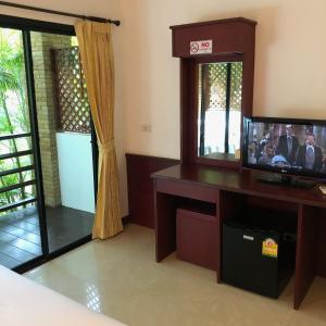 a room with a tv and a desk with a mirror at Noble House Beach Resort in Ko Lanta