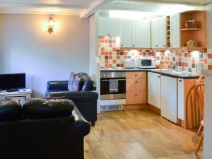 a living room with two couches and a kitchen at Larch Cottage in Craster