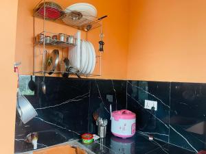 a kitchen with orange walls and a black counter top at Gautam house in Bhairāhawā