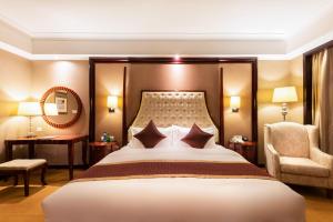 una habitación de hotel con una cama grande y una silla en NH Shenyang Yuhong en Shenyang