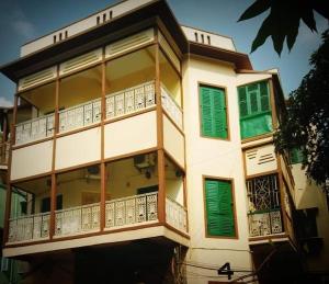 budynek z zielonymi i białymi oknami i balkonami w obiekcie OH Kolkata - Sutanuti Homestay w mieście Kolkata