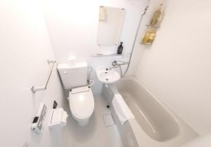 a white bathroom with a toilet and a bath tub at JL HOUSE Kutchan in Kutchan