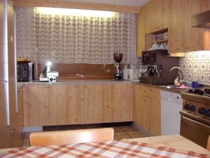 cocina con armarios de madera y encimera en Pension Danler, en Telfes im Stubai