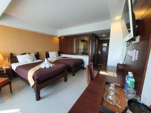 a hotel room with two beds and a dining table at Goldenbell Hotel Chiangmai in Chiang Mai