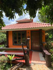 une petite maison orange avec un toit rouge dans l'établissement Baanphuthadol, à Mae Hong Son