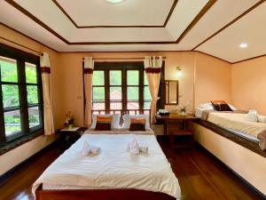 two beds in a room with two windows at Baanphuthadol in Mae Hong Son