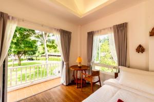 Schlafzimmer mit einem Bett, einem Fenster und einem Tisch in der Unterkunft Phi Private Villa: Luxury Thai with Riverview in Chiang Mai