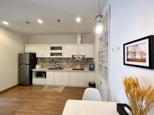 Una cocina con gabinetes blancos y un refrigerador negro. en BOM HOMES- VINHOMES TIMES CITY & PARK hilll, en Hanói