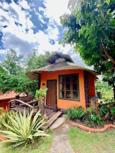 una pequeña casa naranja con porche y puerta en Baanphuthadol, en Mae Hong Son