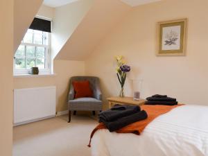 a bedroom with a bed and a chair and a vase of flowers at The Old Gasworks Building in Montrose