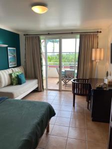 1 dormitorio con cama, mesa y sofá en Studio Tropical avec vue mer dans une résidence hôtelière en Sainte-Luce