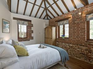 a bedroom with a large bed with a brick wall at Elm Tree Barn in Felmingham