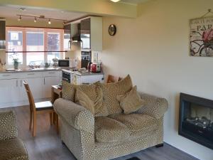 a living room with a couch and a kitchen at Puffin Cottage in Wroxham