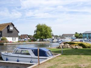 a boat is docked at a dock on the water at Puffin Cottage in Wroxham