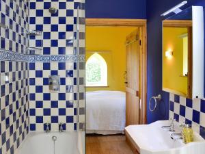 baño con lavabo, bañera y cama en The Byre, en West Stour