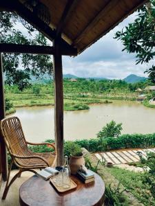 a table and chair with a view of a river at 6Nature Bavi Retreat in Hanoi