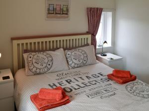 a bedroom with a bed with two red towels on it at Pottergate Cottage in Wroxham