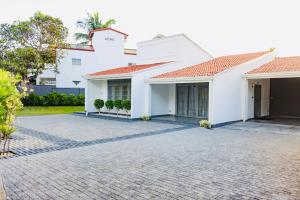 uma casa branca com uma entrada de tijolos em Bony's Holiday Inn Negombo em Negombo
