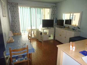 ein Wohnzimmer mit einem Tisch und einem TV sowie eine Küche in der Unterkunft Appartement Port Camargue, 1 pièce, 4 personnes - FR-1-250-196 in Le Grau-du-Roi