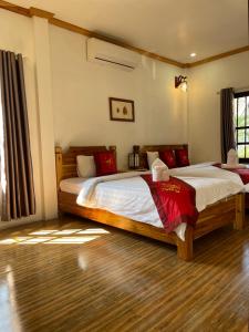 a bedroom with two beds with red pillows at Liberty Place in Luang Prabang