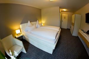 a bedroom with a large white bed and a television at Hotel Eyberg in Dahn