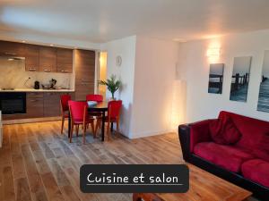 a living room with a red couch and a table and chairs at Appartement calme et pratique. in Tours
