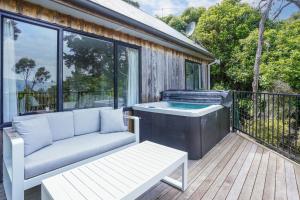 un patio con bañera de hidromasaje y un banco en una terraza en Bushside Cottage - Akaroa Holiday Home, en Akaroa